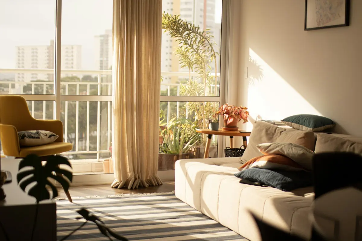 Bright apartment living room with a large window, sofa and plants