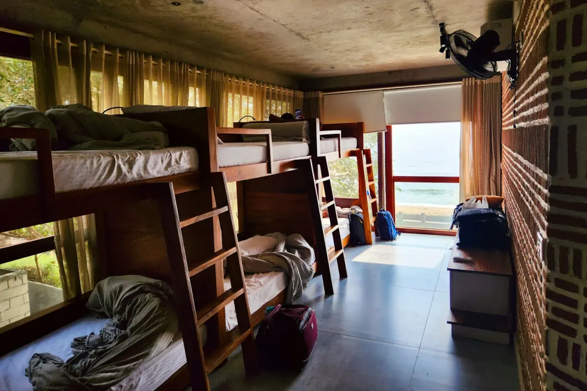 Hostel dorm with wooden bunk beds next to a window